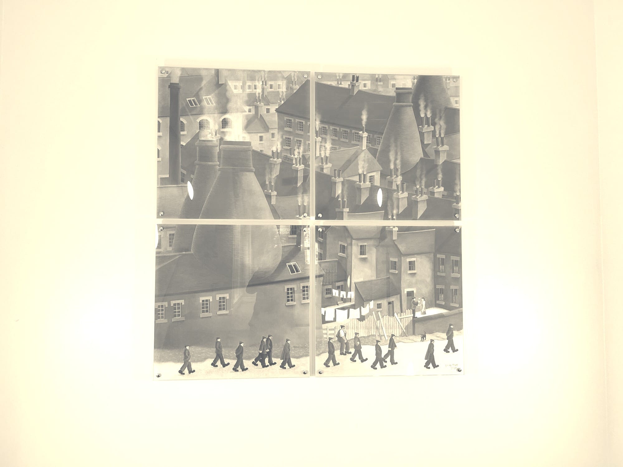 A picture of Victorian factory workers going to work in the potteries. There are distinct bottle kilns (shaped like bottles, local to the area) coming out of the roofs of the buildings. 