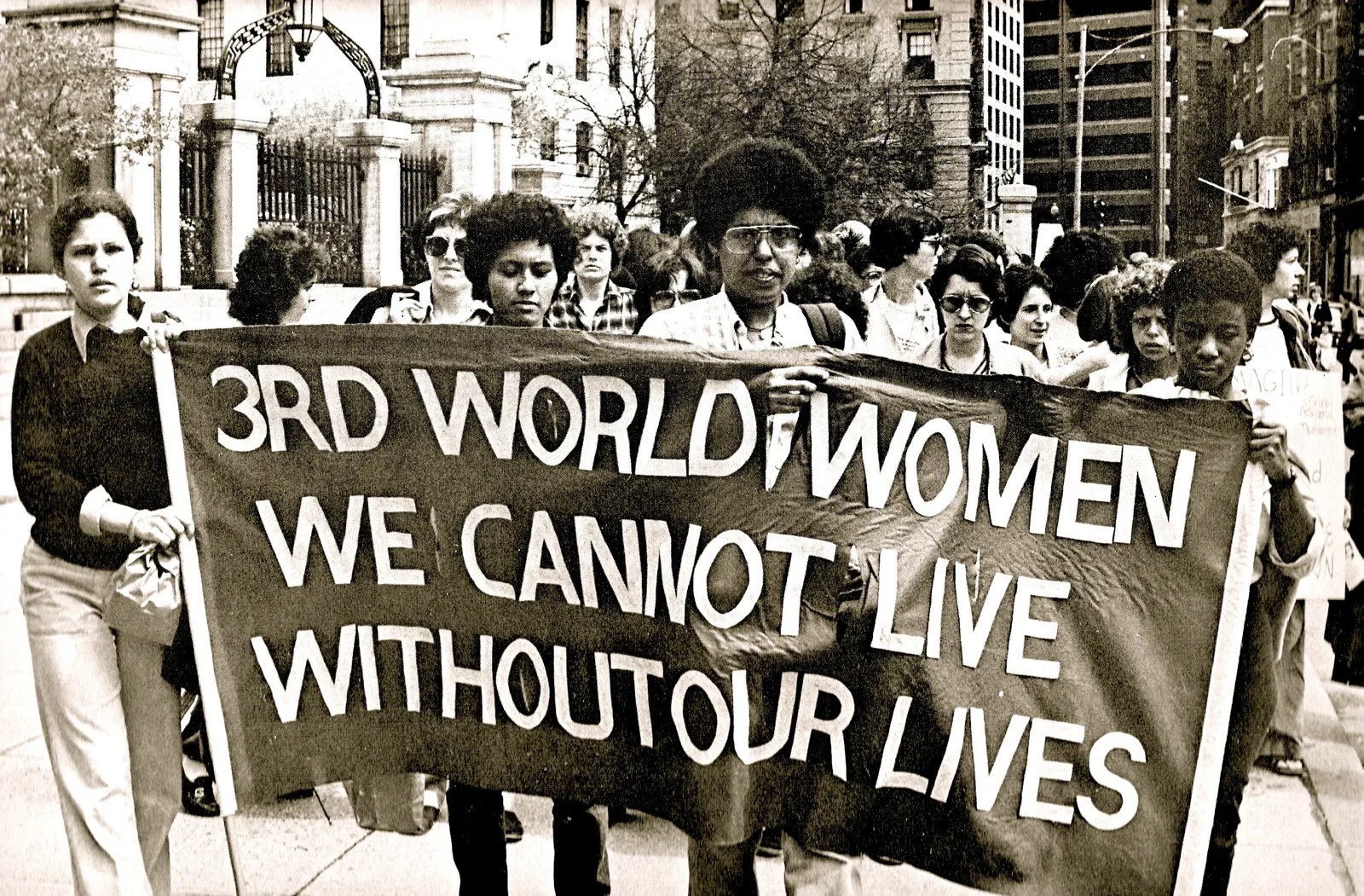 A picture of the Combahee River Collective holding up a banner that reads '3rd World Women We Cannot Live Without Our Lives'